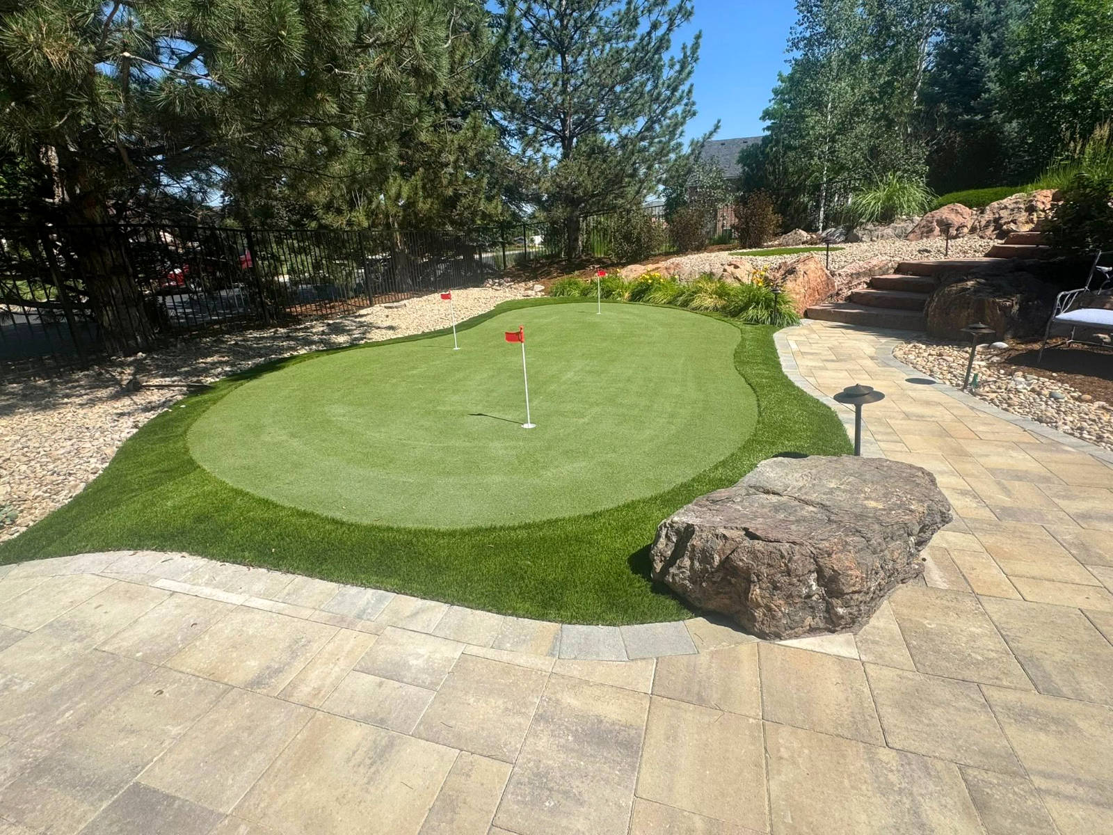 Backyard putting green with red flags set in a paver patio