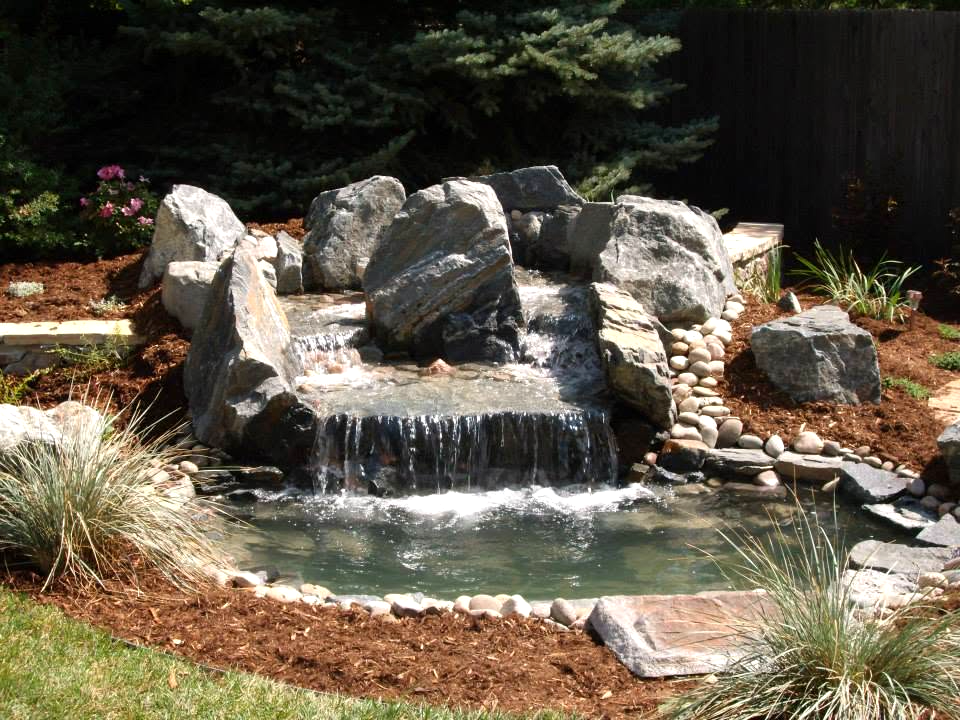Hand-built rock waterfall flowing into a backyard pond